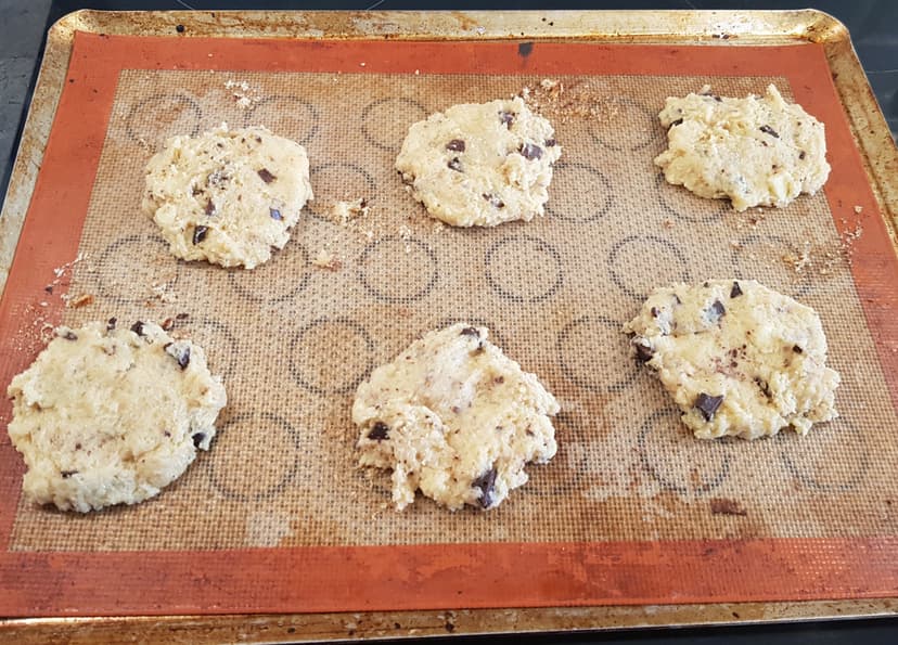 Boules de pâte à cookie aplatis sur une plaque de cuisson 