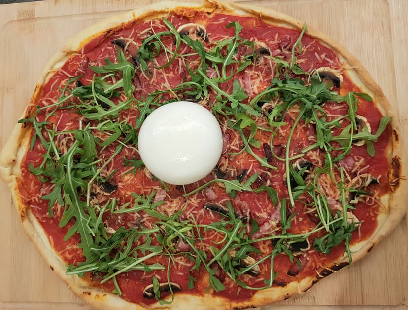 Pizza prête à être dégusté avec roquette et burrata posé dessus 